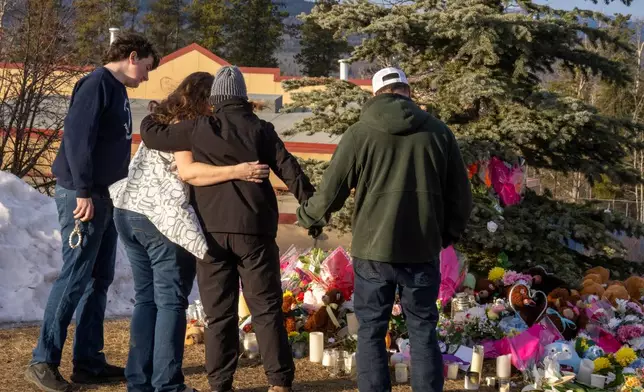 Residents hug as they place flowers at a memorial for the victims of Tuesday's mass shooting in Tumbler Ridge, British Columbia, Canada, on Thursday, Feb. 12, 2026. (Christinne Muschi/The Canadian Press via AP)