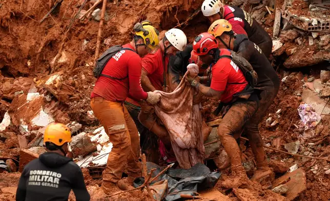 Firefighters recover a body from the site where homes collapsed during heavy rains and severe flooding in the Parque Burnier neighborhood of Juiz de Fora, Minas Gerais state, Brazil, Tuesday, Feb. 24, 2026. (AP Photo/Silvia Izquierdo)