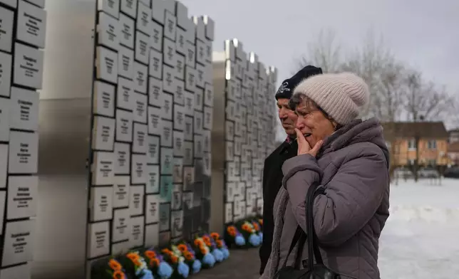 Relatives of those killed during the Russian occupation react at the Wall of Remembrance during a ceremony to mark the fourth anniversary of the Russian invasion of Ukraine, in Bucha, Ukraine, Tuesday, Feb. 24, 2026. (AP Photo/Sergei Grits)