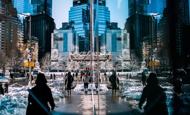 People make their way near piles of plowed snow a day after a winter storm on Tuesday, Feb. 24, 2026, in New York. (AP Photo/Eduardo Munoz Alvarez)