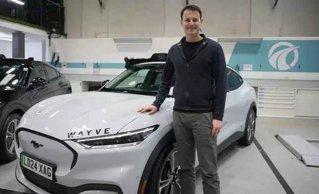 Britain Robotaxis Alex Kendall, co-founder and CEO of Wayve, poses next to an autonomous vehicle during an interview in London, Monday, Feb. 9, 2026. (AP Photo/Kin Cheung)