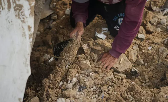 A relative of Mahmoud Hammad helps him search for the remains of his wife, Nema Hammad, who is still buried beneath the rubble of their home destroyed by an Israeli airstrike in December 2023, in Gaza City, Monday, Feb. 9, 2026. (AP Photo/Jehad Alshrafi)