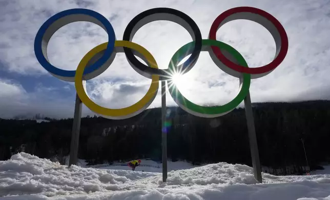 An athlete skis past Olympic rings during a cross country training session at the 2026 Winter Olympics, in Tesero, Italy, Thursday, Feb. 5, 2026. (AP Photo/Kirsty Wigglesworth)