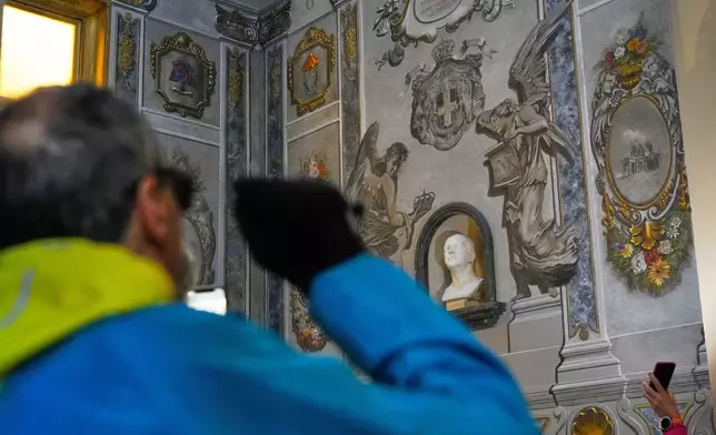 People take pictures at a restored fresco to the memory of late Italy's King Umberto II depicting Angels inside the Basilica of St. Lawrence in Lucina in Rome, Sunday, Feb. 1, 2026. (AP Photo/Gregorio Borgia)