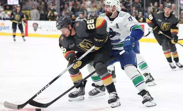Vegas Golden Knights right wing Alexander Holtz (26) skates against Vancouver Canucks defenseman Filip Hronek (17) during the second period of an NHL hockey game Wednesday, Feb. 4, 2026, in Las Vegas. (AP Photo/Ian Maule)