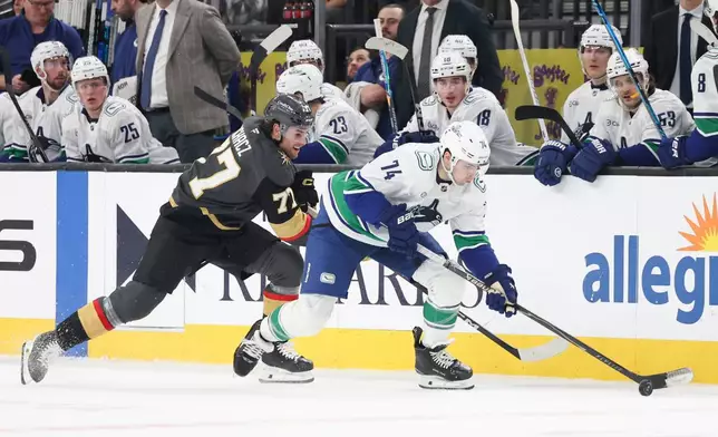 Vancouver Canucks left wing Jake DeBrusk (74) skates against Vegas Golden Knights center Kai Uchacz (77) during the first period of an NHL hockey game Wednesday, Feb. 4, 2026, in Las Vegas. (AP Photo/Ian Maule)