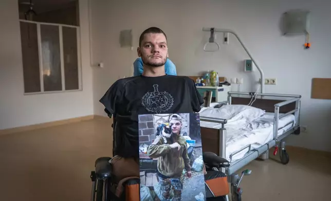 Ruslan Knysh, 20, a war veteran, sits in a wheelchair with a photograph of himself taken before he lost his limbs in a drone attack last year, in Kyiv, Ukraine, Sunday, Feb. 22, 2026. (AP Photo/Dan Bashakov)