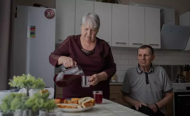 Liudmyla Shytik, 77, pours a drink for her husband Viktor, 78, in their social housing apartment in the Kyiv region of Ukraine, Wednesday, Feb. 18, 2026. (AP Photo/Efrem Lukatsky)