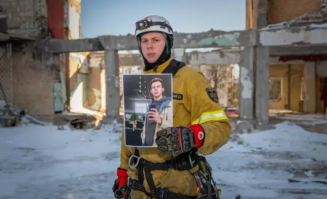 Ivan Khmelnytskyi, 25, a rescue worker, poses with a photograph of himself working in a call center before Russia's full-scale invasion, as he stands inside a residential building damaged by a Russian strike to which he responded in Kyiv, Ukraine, Saturday, Feb. 21, 2026. (AP Photo/Dan Bashakov)