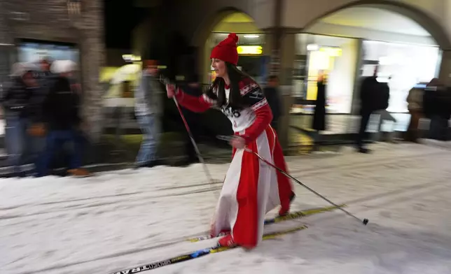 Spectators watch from alongside a snow track as Bormio residents compete in an annual cross-country ski race through the streets of the old town, this year coinciding with the 2026 Winter Olympics, in Bormio, Italy, Friday, Feb. 13, 2026. (AP Photo/Rebecca Blackwell)