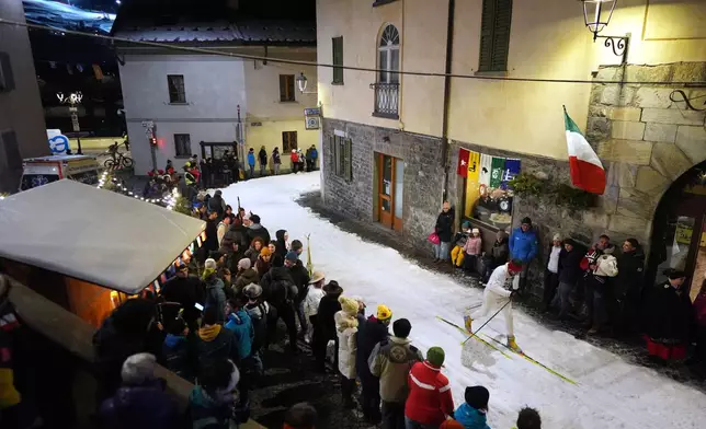 Spectators watch as Bormio residents compete in an annual cross-country ski race through the streets of the old town, this year coinciding with the 2026 Winter Olympics, in Bormio, Italy, Friday, Feb. 13, 2026. (AP Photo/Rebecca Blackwell)