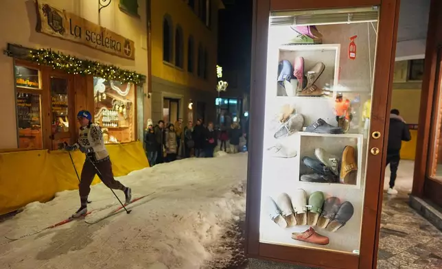 A participant skis past storefronts as Bormio residents compete in an annual cross-country ski race through the streets of the old town, this year coinciding with the 2026 Winter Olympics, in Bormio, Italy, Friday, Feb. 13, 2026. (AP Photo/Rebecca Blackwell)