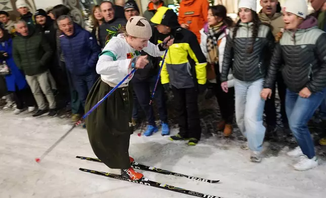 Spectators cheer on a participant as Bormio residents compete in an annual cross-country ski race through the streets of the old town, this year coinciding with the 2026 Winter Olympics, in Bormio, Italy, Friday, Feb. 13, 2026. (AP Photo/Rebecca Blackwell)