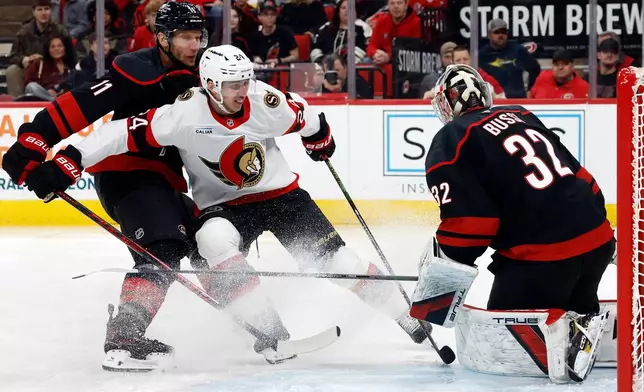 Ottawa Senators' Dylan Cozens has his shot blocked by Carolina Hurricanes goaltender Brandon Bussi (32) with Jordan Staal nearby during the first period of an NHL hockey game in Raleigh, N.C., Tuesday, Feb. 3, 2026. (AP Photo/Karl DeBlaker)