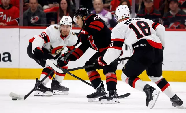 Carolina Hurricanes' Logan Stankoven (22) carries the puck between Ottawa Senators' Jake Sanderson (85) and Tim Stützle (18) during the first period of an NHL hockey game in Raleigh, N.C., Tuesday, Feb. 3, 2026. (AP Photo/Karl DeBlaker)