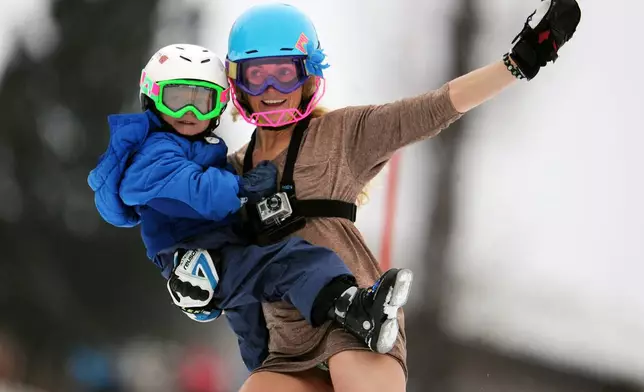 FILE - Sarah Schleper holds her son Lasse as she skies down the course during an alpine ski, women's World Cup slalom, in Lienz, Austria, Thursday, Dec. 29, 2011. (AP Photo/Giovanni Auletta, File)