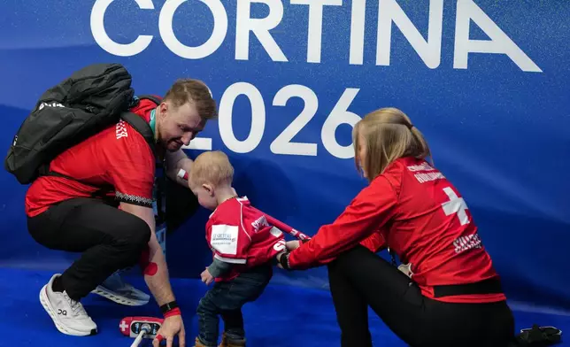 Switzerland's Yannick Schwaller and Briar Schwaller-Huerlimann interact with their child after the mixed doubles round robin phase of the curling competition against Canada, at the 2026 Winter Olympics, in Cortina d'Ampezzo, Italy, Sunday, Feb. 8, 2026. (AP Photo/Misper Apawu)