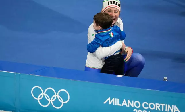 Francesca Lollobrigida of Italy celebrates with her son Tommaso after winning the gold medal in the women's 3,000 meters speedskating race at the 2026 Winter Olympics, in Milan, Italy, Saturday, Feb. 7, 2026. (AP Photo/Luca Bruno)