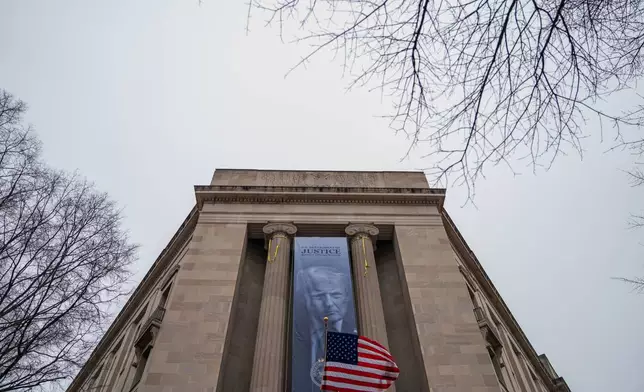A banner showing President Donald Trump is hung from the Department of Justice, Thursday, Feb. 19, 2026, in Washington. (AP Photo/Allison Robbert)