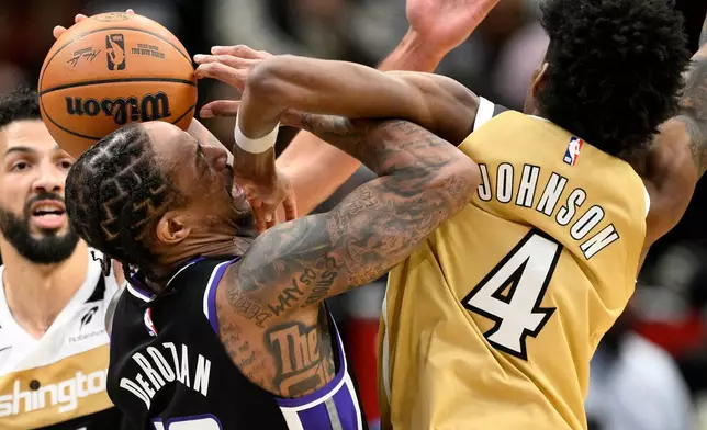 Washington Wizards guard AJ Johnson (4) fouls Sacramento Kings guard DeMar DeRozan, front left, during the first half of an NBA basketball game, Sunday, Feb. 1, 2026, in Washington. (AP Photo/Nick Wass)