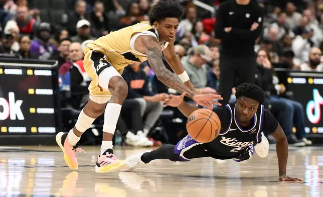 Sacramento Kings guard Isaiah Stevens, right, and Washington Wizards guard AJ Johnson, left, battle for the ball during the first half of an NBA basketball game, Sunday, Feb. 1, 2026, in Washington. (AP Photo/Nick Wass)