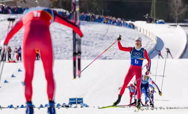 Einar Hedegart, of Norway, bows to teammate Johannes Hoesflot Klaebo approaching the finish line to win the gold medal in the cross-country skiing men's team sprint free at the 2026 Winter Olympics, in Tesero, Italy, Wednesday, Feb. 18, 2026. (AP Photo/Kirsty Wigglesworth)