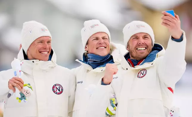 Silver medalist Martin Loewstroem Nyenget, gold medalist Johannes Hoesflot Klaebo and bronze medalist Emil Iversen, all three of Norway, pose on the podium of the cross country skiing men's 50km mass start Classic at the 2026 Winter Olympics, in Tesero, Italy, Saturday, Feb. 21, 2026. (AP Photo/Matthias Schrader)