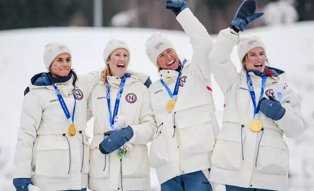 Heidi Weng, Karoline Simpson-Larsen, Astrid Oeyre Slind, and Kristin Austgulen Fosnaes, of Norway, celebrate on the podium after winning the gold medal in the cross country skiing women's 4 x 7.5km relay at the 2026 Winter Olympics, in Tesero, Italy, Saturday, Feb. 14, 2026. (AP Photo/Matthias Schrader)