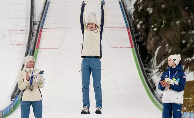 Gold medalist Anna Odine Stroem, of Norway, celebrates on the podium flanked by silver medalist Eirin Maria Kvandal, also of Norway, and bronze medalist Nika Prevc, of Slovenia, right, after the ski jumping women's large hill individual at the 2026 Winter Olympics, in Predazzo, Italy, Sunday, Feb. 15, 2026. (AP Photo/Kirsty Wigglesworth)