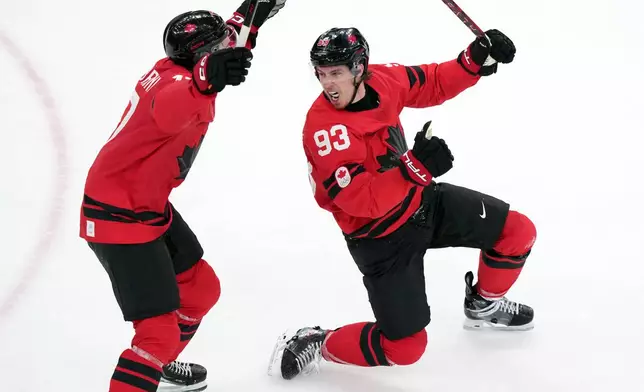 Canada's Mitch Marner (93) and Macklin Celebrini (17) celebrate after Marner scored the winning goal during the overtime period of a men's ice hockey quarterfinal game between Canada and Czechia at the 2026 Winter Olympics, in Milan, Italy, Wednesday, Feb. 18, 2026. (AP Photo/Carolyn Kaster)