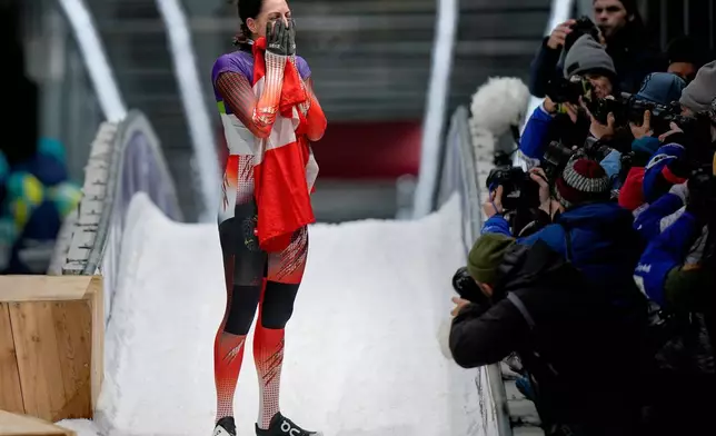 Austria's gold medalist Janine Flock celebrates as she arrives at the finish during a women's skeleton run at the 2026 Winter Olympics, in Cortina d'Ampezzo, Italy, Saturday, Feb. 14, 2026. (AP Photo/Aijaz Rahi)