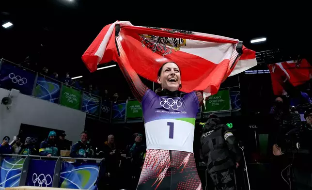 Austria's gold medalist Janine Flock celebrates as she arrives at the finish during a women's skeleton run at the 2026 Winter Olympics, in Cortina d'Ampezzo, Italy, Saturday, Feb. 14, 2026. (AP Photo/Alessandra Tarantino)