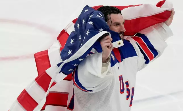 United States' Connor Hellebuyck (37) skates around the ice with the American flag after the US defeated Canada in the men's ice hockey gold medal game at the 2026 Winter Olympics, in Milan, Italy, Sunday, Feb. 22, 2026. (AP Photo/Luca Bruno)