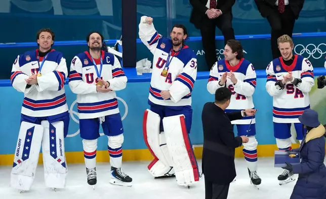 United States goalkeeper Connor Hellebuyck (37) celebrates as player receive their medals after defeating Canada in overtime to win the men's ice hockey gold medal game at the 2026 Winter Olympics in Milan, Italy, Sunday, Feb. 22, 2026. (AP Photo/Carolyn Kaster)