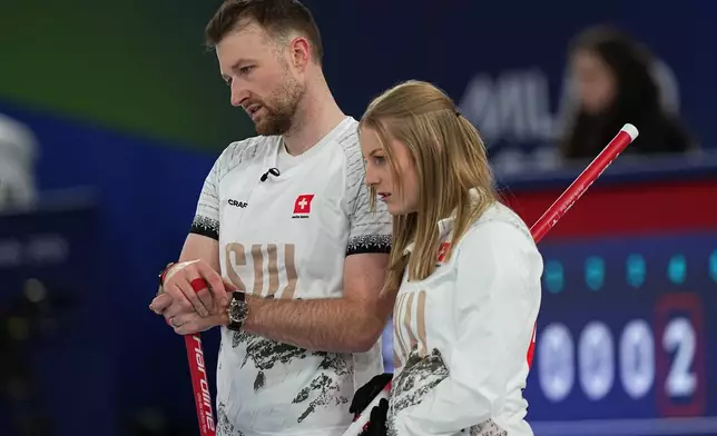 Switzerland's Yannick Schwaller, left, and Yannick Schwaller strategize during the mixed doubles round robin phase of the curling competition against Czechia at the 2026 Winter Olympics, in Cortina d'Ampezzo, Italy, Saturday, Feb. 7, 2026. (AP Photo/Fatima Shbair)