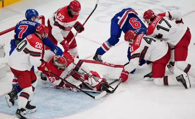 Denmark's goalkeeper Mads Sogaard, center, makes a save during a preliminary round match of men's ice hockey between United States and Denmark at the 2026 Winter Olympics, in Milan, Italy, Saturday, Feb. 14, 2026. (AP Photo/Petr David Josek)