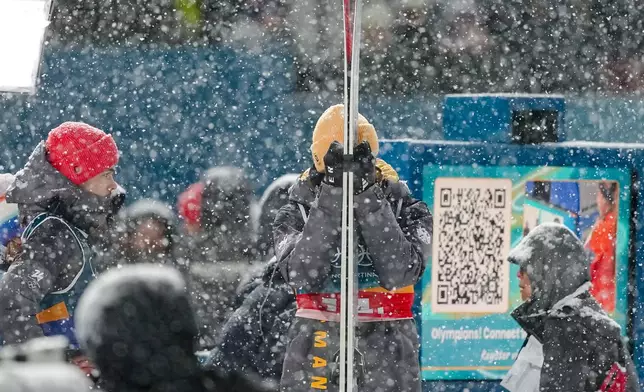 Andreas Wellinger, center, and Philipp Raimund, of Germany, left, react as a snowfall interrupts the final round jump of the ski jumping men's super team competition at the 2026 Winter Olympics, in Predazzo, Italy, Monday, Feb. 16, 2026. (AP Photo/Matthias Schrader)