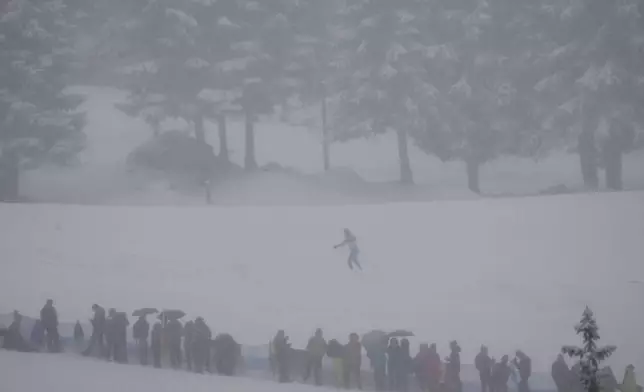 Spectators watch a skier as he trains before the Biathlon Men's 4 x 7.5km Relay at the 2026 Winter Olympics, in Anterselva, Italy, Tuesday, Feb. 17, 2026. (AP Photo/Christophe Ena)