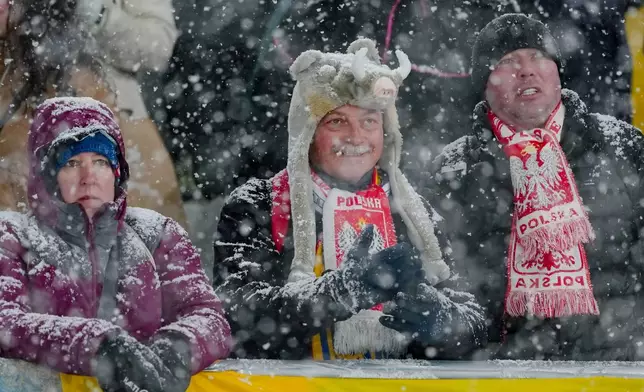 Poland fans wait while a snowfall interrupts the final round jump of the ski jumping men's super team competition at the 2026 Winter Olympics, in Predazzo, Italy, Monday, Feb. 16, 2026. (AP Photo/Matthias Schrader)
