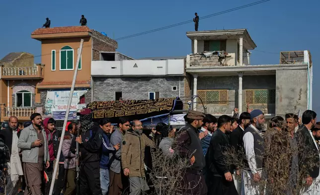 Police commandos take position on rooftops to ensure security as mourners carry the coffin of a victim of Friday's suicide bombing inside a Shiite mosque, for a funeral prayer, in Islamabad, Pakistan, Saturday, Feb. 7, 2026. (AP Photo/Anjum Naveed)
