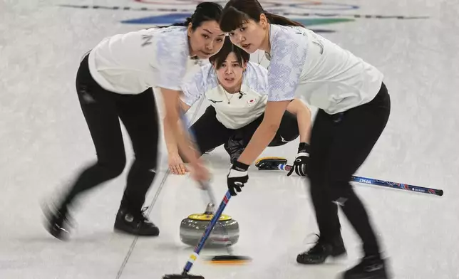 Japan's Yuna Kotani, Anna Ohmiya and Kaho Onodera in action during the women's curling round robin session against Britain at the 2026 Winter Olympics, in Cortina d'Ampezzo, Italy, Wednesday, Feb. 18, 2026. (AP Photo/Fatima Shbair)