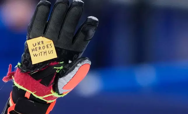 Ukraine's Dmytro Shepiuk holds a sticker reading "UKR heroes with us" at the finish area during a men's super-G race, at the 2026 Winter Olympics, in Bormio, Italy, Wednesday, Feb.11, 2026. (AP Photo/Julia Demaree Nikhinson)