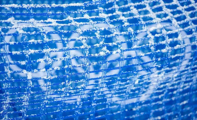 Snow gathers on a net fence at the ski jumping venue ahead of the nordic combined team sprint at the 2026 Winter Olympics, in Predazzo, Italy, Thursday, Feb. 19, 2026. (AP Photo/Matthias Schrader)