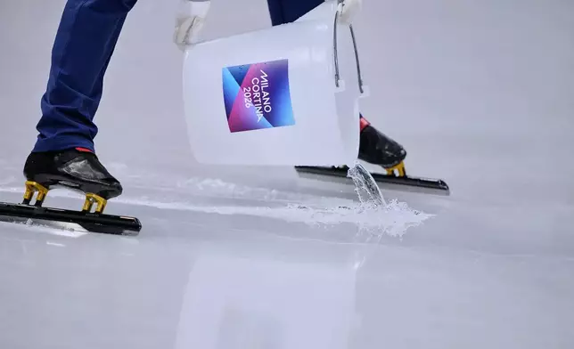 A worker pours water on the ice between races during a short track speed skating women's 1500 meters semifinal at the 2026 Winter Olympics, in Milan, Italy, Friday, Feb. 20, 2026. (AP Photo/Natacha Pisarenko)