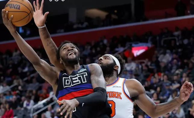 Detroit Pistons forward Paul Reed, left, lays up a shot against New York Knicks center Mitchell Robinson, right, during the second half of an NBA basketball game Friday, Feb. 6, 2026, in Detroit. (AP Photo/Duane Burleson)