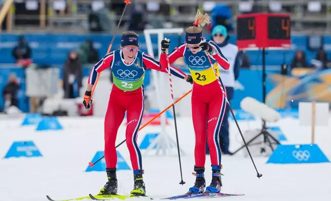Astrid Oeyre Slind, of Norway, tags teammate Karoline Simpson-Larsen, right, during the cross country skiing women's 4 x 7.5km relay at the 2026 Winter Olympics, in Tesero, Italy, Saturday, Feb. 14, 2026. (AP Photo/Kirsty Wigglesworth)