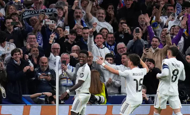 Real Madrid's Vinicius Junior, left, celebrates with teammates after scoring his side's second goal during the second leg of the Champions League playoff soccer match between Real Madrid and Benfica in Madrid, Spain, Wednesday, Feb. 25, 2026. (AP Photo/Manu Fernandez)