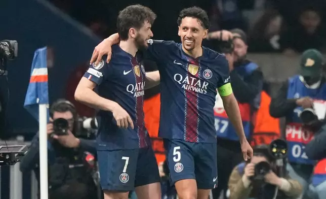 PSG's Khvicha Kvaratskhelia.left, and Marquinhos hug after a goal during a Champions League second leg playoff soccer match between Paris Saint-Germain and Monaco in Paris Wednesday, Feb. 25, 2026. (AP Photo/Michel Euler)