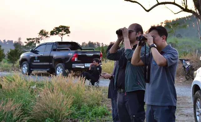 In this photo released by Thailand Department of National Parks, Wildlife and Plant Conservation, officials use a pair of binoculars to monitor wild elephants after they received elephant contraception vaccines in the Trat province of Thailand, Tuesday, Jan. 27, 2026. (Thailand Department of National Parks, Wildlife and Plant Conservation via AP)