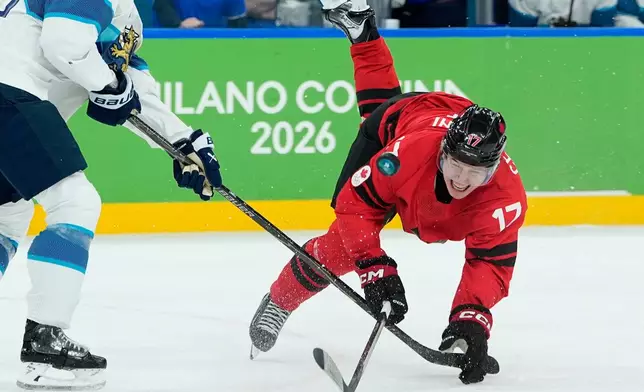 Finland's Esa Lindell (23) challenges for the puck with Canada's Macklin Celebrini (17) during a men's ice hockey semifinal game between Canada and Finland at the 2026 Winter Olympics, in Milan, Italy, Friday, Feb. 20, 2026. (AP Photo/Petr David Josek)